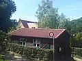 Baracke, die vor dem Bau des Gemeindeszentrums (im Hintergrund) für Gottesdienste genutzt wurde