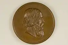 Das Foto zeigt die Vorderseite der bronzen Graefe-Medaille. In der Mitte ist Albert von Graefes Porträt im Profil mit Blick nach rechts erhaben geprägt. Es wird umrahmt mit dem in der oberen Hälfte am Rand in Versalien geprägten Namen „ALBRECHTVS • DE • GRAEFE“. Die untere Hälfte, abgesetzt von der oberen durch jeweils einem fünfzackigen Stern, zeigt die folgende Daten in römischer Ziffern „N • D • XXII • M • MAI • A • MDCCCXXVII • M • D • XX • M • IVL • A • MDCCCLXX“. Unterhalb des Halses befindet sich eine Signatur: „F. Hartzer FEC. E. Weigand SC“