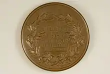 Die Rückseite der bronzenen Graefe-Medaille zeigt sieben zentrierten geprägte Zeilen jeweils in Versalschrift: „HERMANNO“, „DE • HELMHOLTZ“, „D • D“, „SOCIETES“, „OPTHALMOLOGICA“, „HEIDELBERGAE“, „A • MDCCCLXXXVI“. Der Schriftblock wird durch ein Lorbeerkranz gerahmt. Oben am Rand sind die beiden Worte „PRAEMIVM“ „GRAEFIANVM“ wiederum Versalschrift eingeprägt