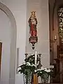 Im Mai geschmückte Marienstatue am linken Chorpfeiler