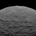Ansicht von Ceres von Dawn. Die Nord­seite von Ahuna Mons ragt über den Horizont hinaus. Norden befindet sich unten