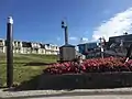 Sturmflutpfahl neben der Freitreppe, der alte Leuchtturm dahinter, im Blumenbeet eine Treibmine und ein Stockanker