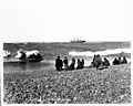 Yupik am Ufer, mit dem Dampfschiff Corwin im Hintergrund (1907)
